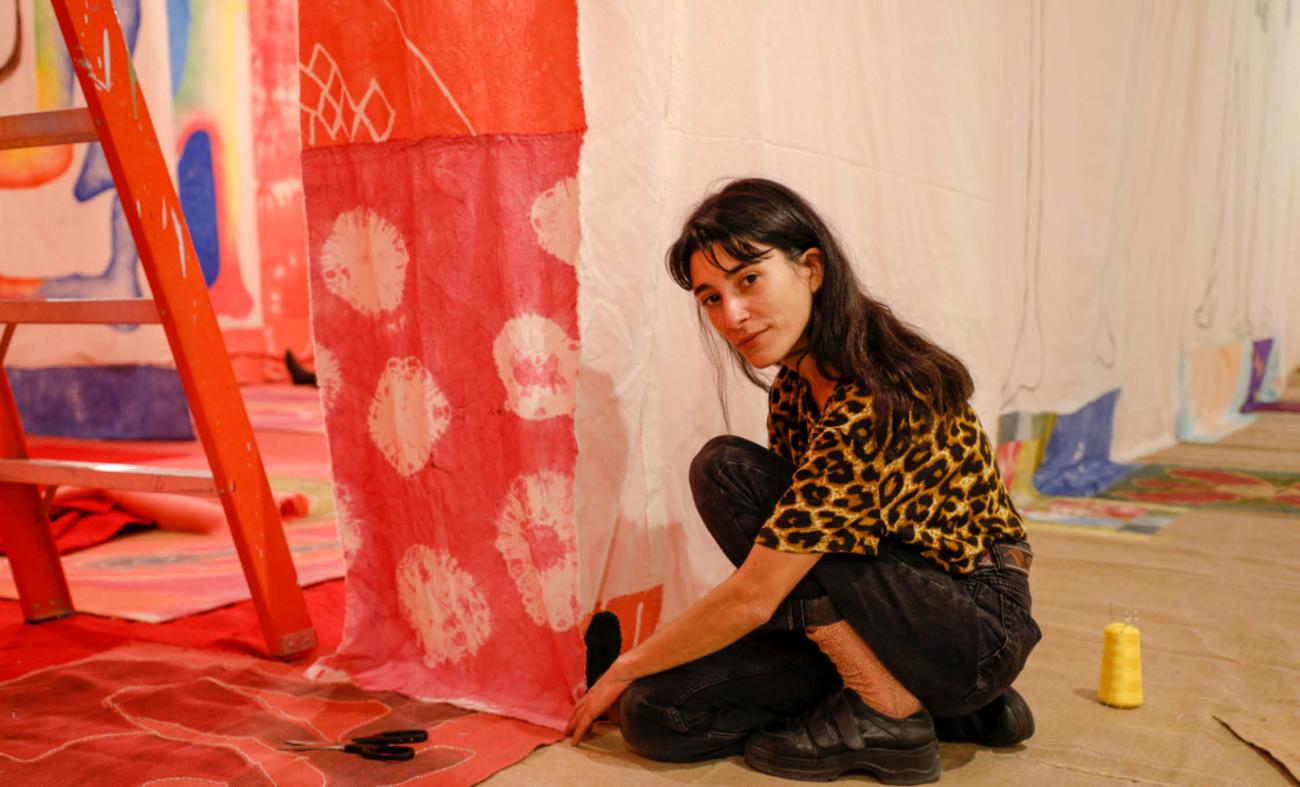Kunstenares Celina Eceiza installeert een doek in haar Rubyfruit Jungle tentoonstelling