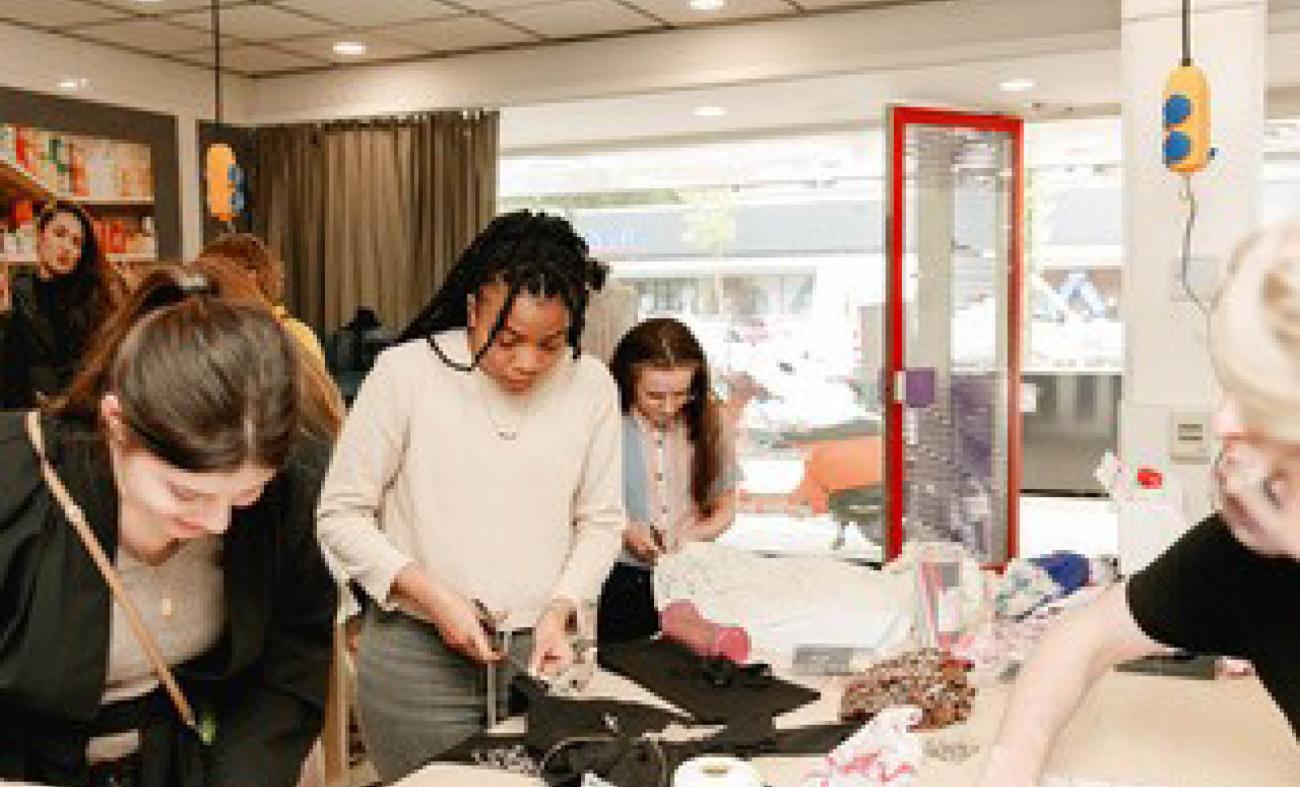 groep cursisten die samen bezig zijn met kleding naaien