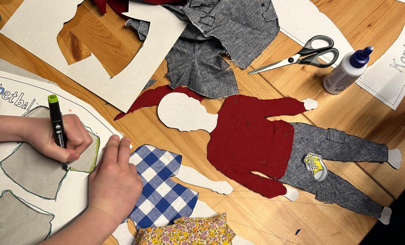foto van kinderknutselwerkjes, zoals papieren aankleedpoppen, van oude stofjes