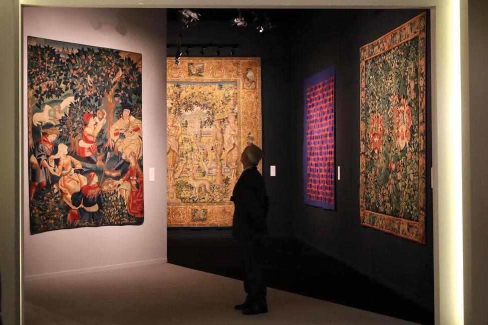 Man tussen schilderijen op kunstmarkt